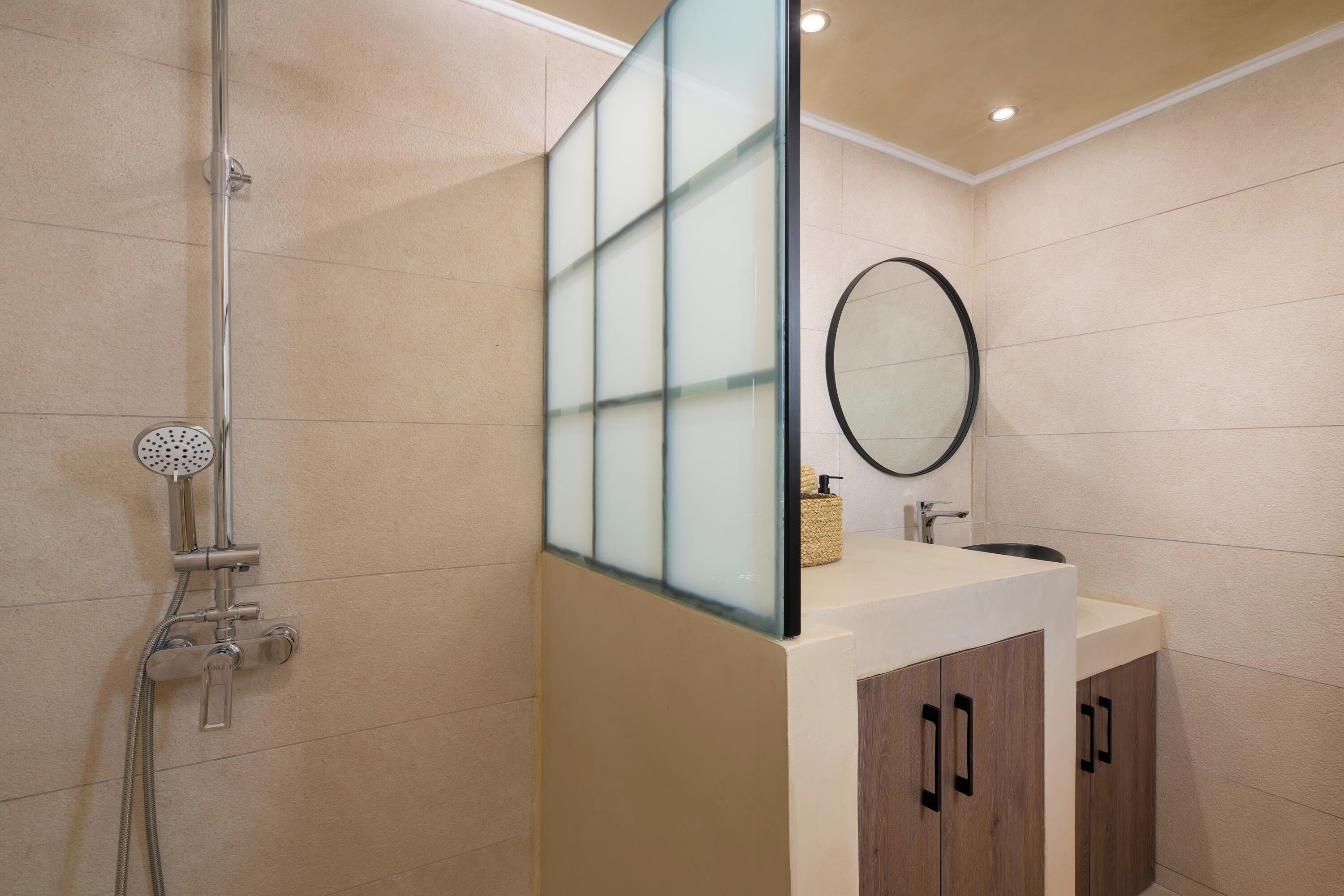 Ein modernes Badezimmer mit Glasabtrennung, Dusche, Waschbecken und Holzschränken.