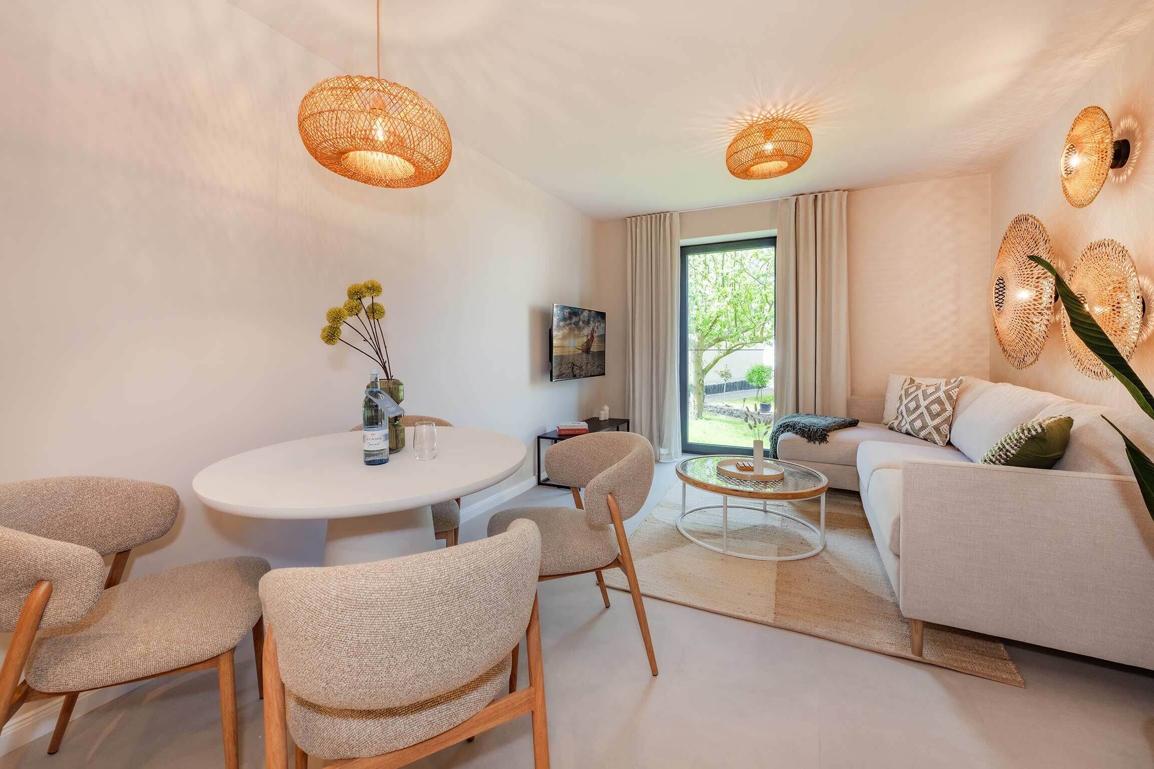 A modern living room with a round dining table, two sofas, and a large window.