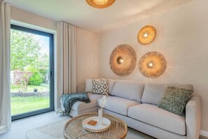 Ein modernes Wohnzimmer mit einer Couch, einem runden Couchtisch und einem großen Fenster mit Vorhängen.