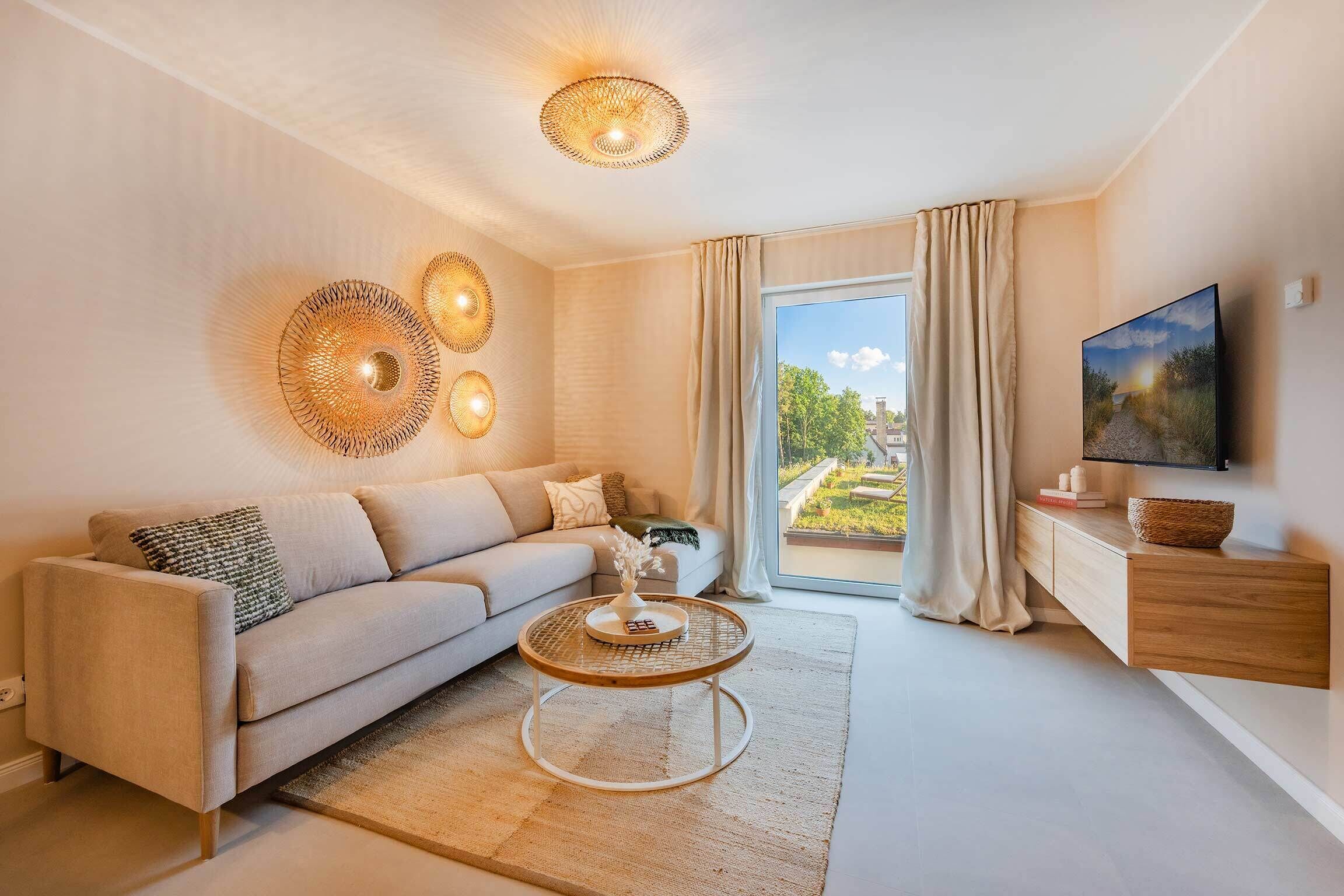 A modern living room with a sofa, a coffee table, a TV, and a large window with curtains.