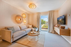 A modern living room with a sofa, a coffee table, a TV, and a large window with curtains. - Bali Blizz apartment 18 with sauna, whirlpool and terrace in Benz (Benz)