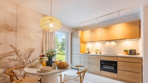 A modern kitchen with wooden cabinets, a built-in oven, and a dining area with a round table and chairs. - Bali Blizz apartment 18 with sauna, whirlpool and terrace in Benz (Benz)