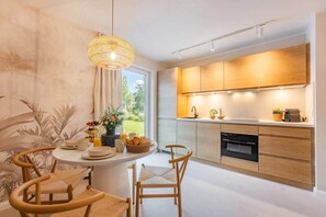 A modern kitchen with wooden cabinets, a built-in oven, and a dining area with a round table and chairs. - Bali Blizz apartment 18 with sauna, whirlpool and terrace in Benz (Benz)