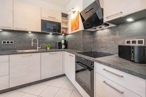 A modern kitchen with a built-in oven, microwave, and coffee maker. - House Dünenwald 15 - Sunny Island: 57 m², terrace & 300 m to the sandy beach (Zinnowitz)