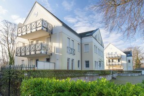 A multi-story residential building with balconies, a gated entrance, and a well-maintained garden. - Vrbo Property (Zinnowitz)