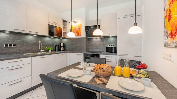 Cozinha moderna com ilha central, iluminação pendente e espaço para café da manhã.