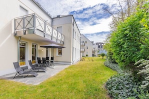 A modern house with a balcony, a patio with chairs, and a well-maintained lawn. - House Dünenwald 15 - Sunny Island: 57 m², terrace & 300 m to the sandy beach (Zinnowitz)