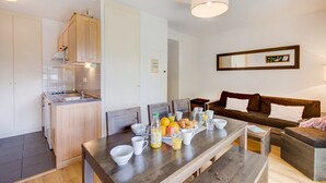 Una cucina moderna con mobili in legno, un tavolo da pranzo apparecchiato per la colazione e un divano marrone nella zona soggiorno.