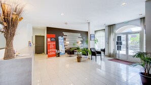 Un moderno vestíbulo de hotel con mostrador de recepción, zona de estar y grandes ventanales.