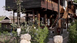A wooden house with a porch, two stone elephant statues, and a brick pathway. - Baan Rim Doi Maerim (Mae Rim)