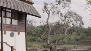 A building with a tiled roof, a wooden bench, a large planter, and a gravel path. - Baan Rim Doi Maerim (Mae Rim)