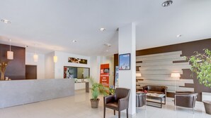 Een moderne hotellobby met een receptiebalie, een zithoek en een grote poster die een ski-evenement promoot.