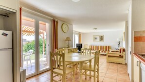 A kitchen with a dining table and chairs, a refrigerator, and a sliding glass door leading to an outdoor patio. - Home for 4 with Private Parking (HOMPS (AUDE))