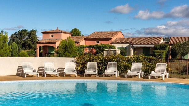 A swimming pool with lounge chairs, a building with a tiled roof, and greenery in the background. - Home for 4 with Private Parking (HOMPS (AUDE))