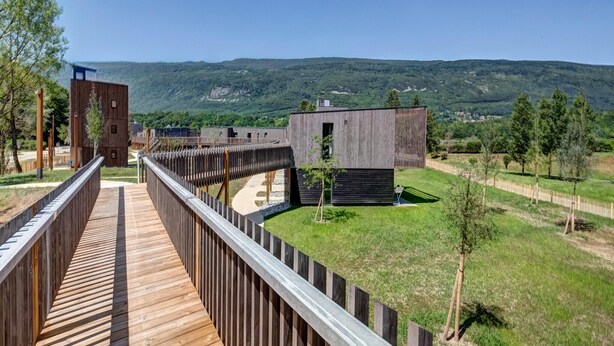 Eine Holzterrasse führt zu einem Gebäude mit Blick auf eine hügelige Landschaft.