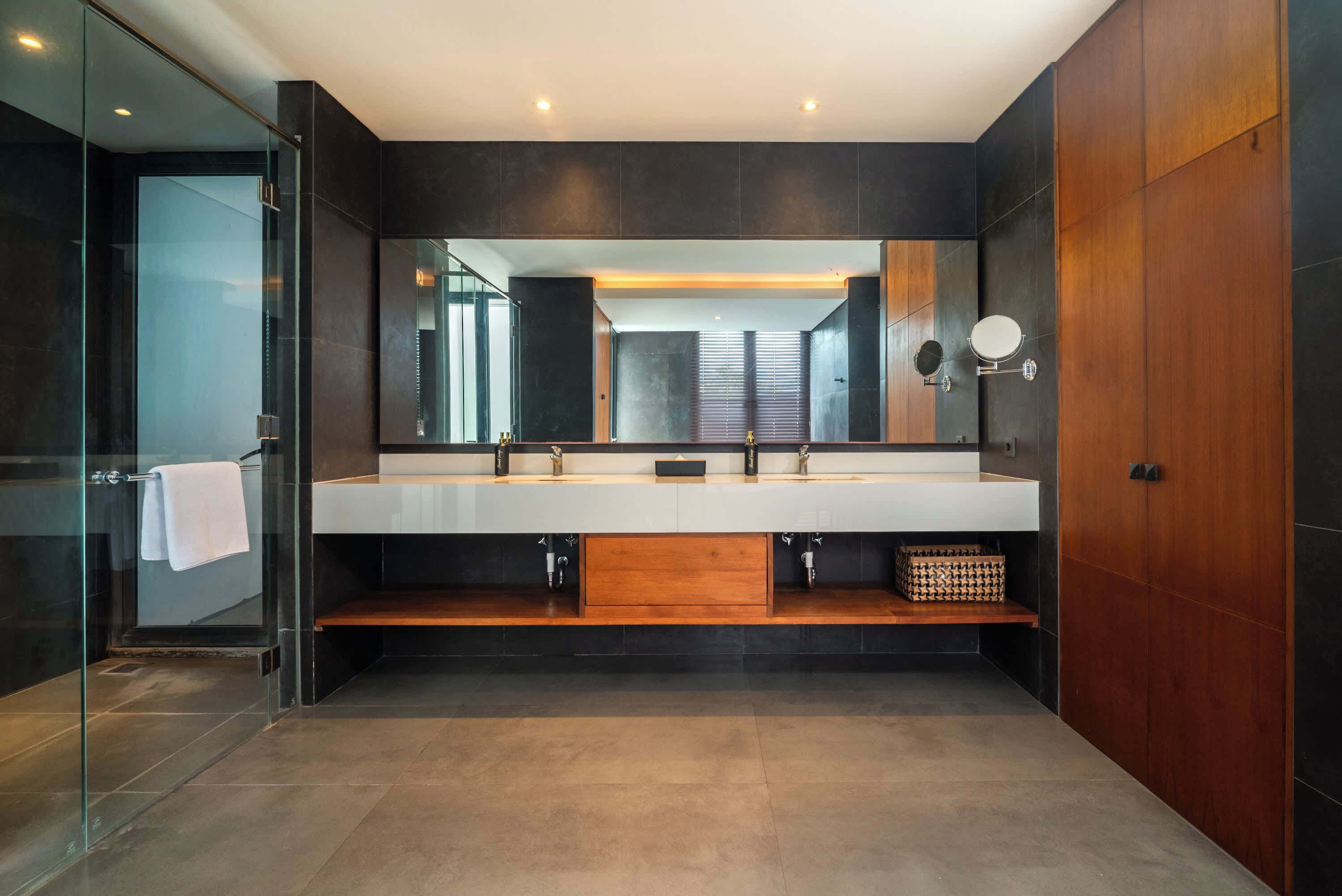 A modern bathroom with a large mirror, two sinks, and a wooden cabinet.