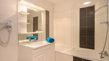A bathroom with a white sink, mirror, and a shower area.