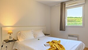 Ein Hotelzimmer mit einem Bett, einer Nachttischlampe, einem Fenster mit Vorhängen und einer Heizung.