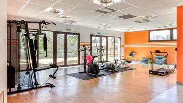 Une salle de sport équipée de machines de cardio, de matériel de musculation et dotée d’une grande fenêtre laissant entrer la lumière naturelle.