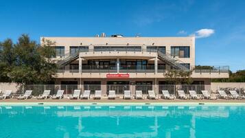 Un bâtiment moderne doté d’une piscine, d’un restaurant et de chaises longues.