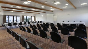 Uma sala de conferências com fileiras de cadeiras, um quadro branco e mesas.