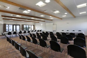 Ein Konferenzraum mit Reihen von Stühlen, einer Whiteboard und Tischen.