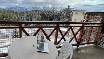 Un balcon avec une table et des chaises, un ordinateur portable et une tasse.