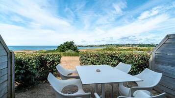 Un patio con mesa y sillas, con vistas a una playa y una extensión de agua.