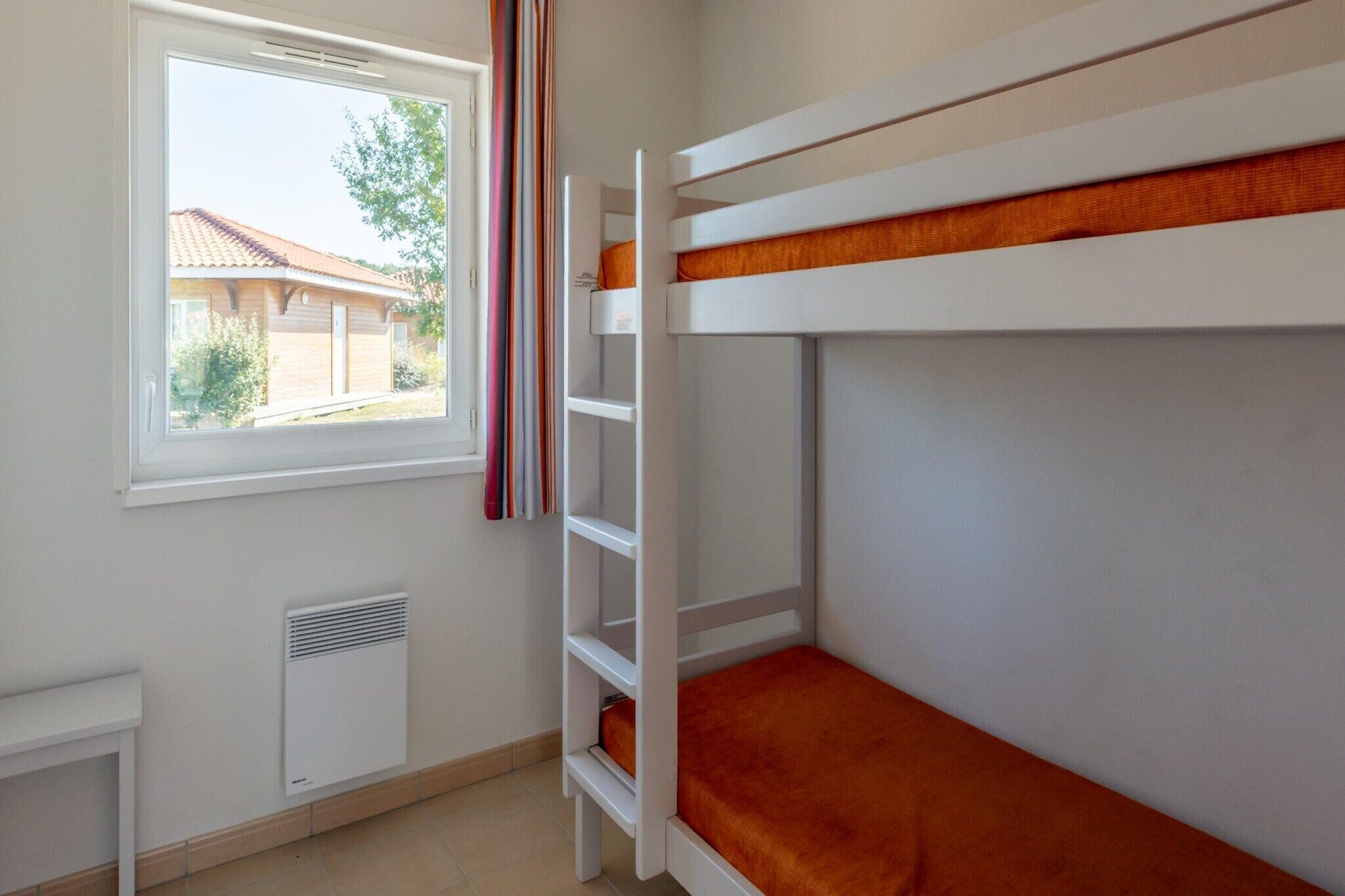 Ein Schlafraum mit Etagenbetten, einem Fenster, einem Heizkörper und einem kleinen Tisch.