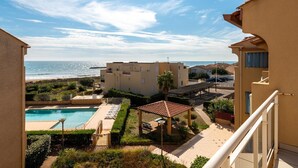 En boligbygning med swimmingpool, overdækket terrasse og havudsigt.