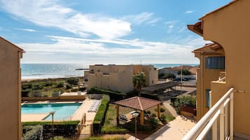 Ein Wohngebäude mit Swimmingpool, einer überdachten Terrasse und Meerblick.