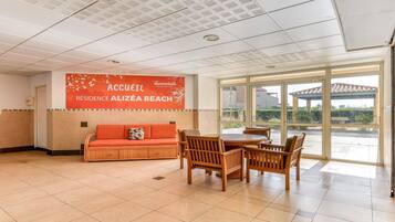 Eine geräumige Lobby mit einem großen Fenster, einem Empfangsschalter und einer Sitzecke mit einer Couch und Holzstühlen.
