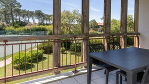 A balcony with a table and chairs, overlooking a tennis court and greenery. - Coastal Retreat near Sandy Beach (SERIGNAN (HÉRAULT))