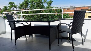 Ein Balkon mit Tisch und Stühlen, einem Geländer und Gebäuden im Hintergrund.