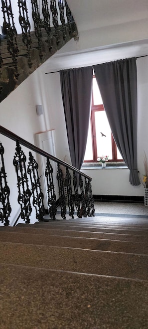 Eine Treppe mit aufwendiger schwarzer Geländer zu einer Zwischenebene.