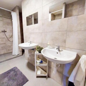 Ein modernes Badezimmer mit zwei Waschbecken, einer Dusche und einem Spiegel.