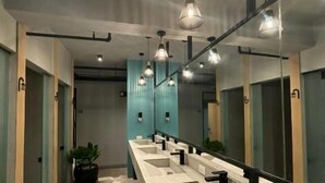 Un baño moderno con varios lavamanos, suelo con estampado geométrico e iluminación colgante.