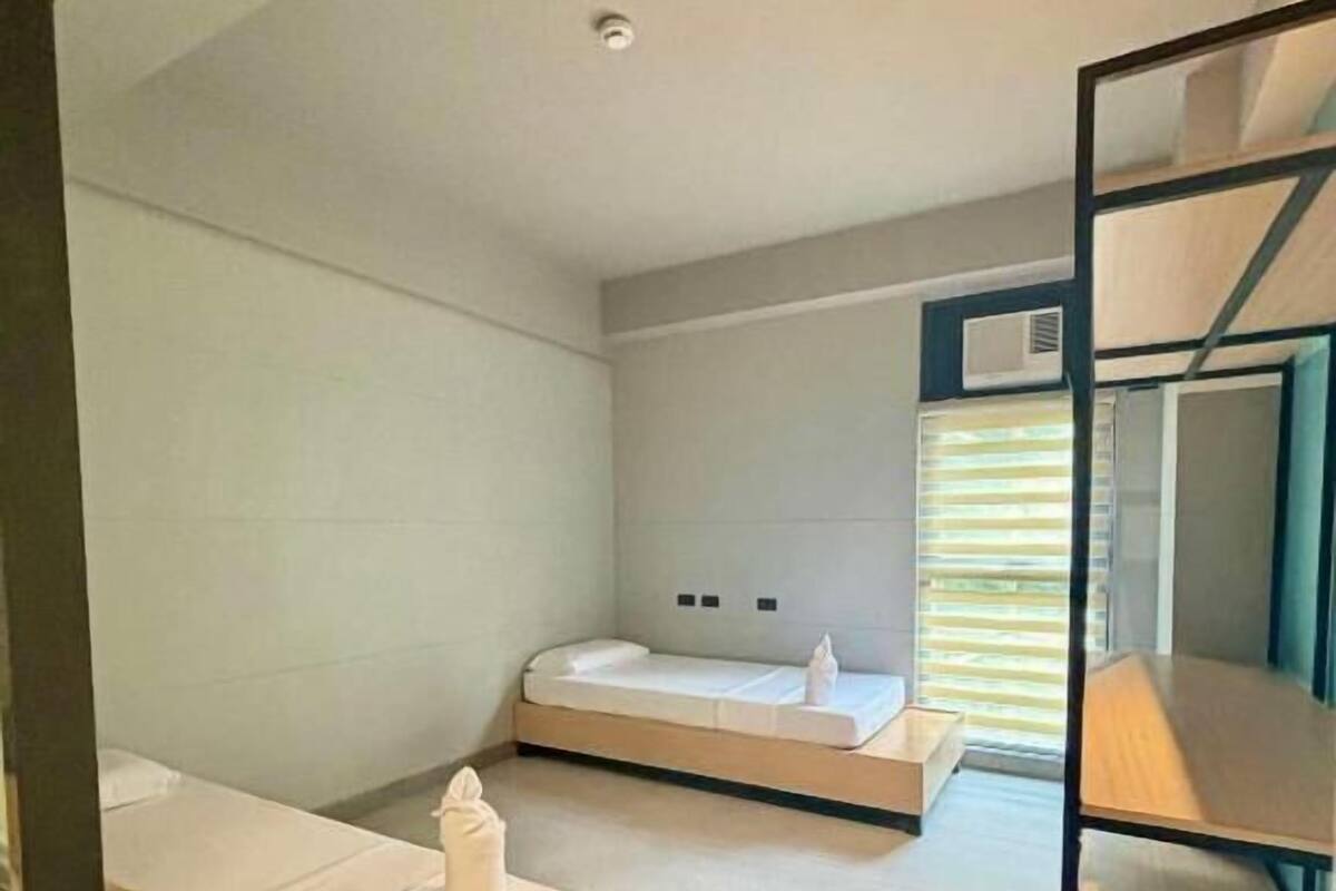 Una habitación de hotel moderna con una cama, un sofá, una mesita de madera y un estante empotrado.