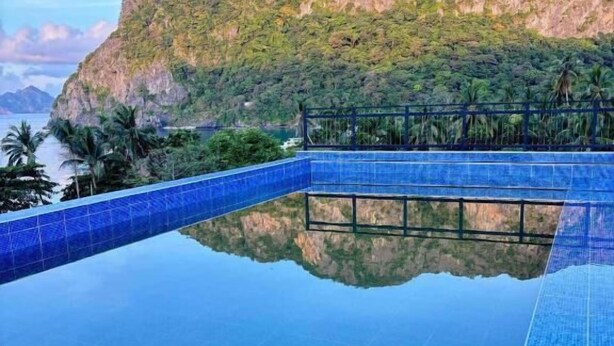 Una piscina infinita de color azul intenso con montañas al fondo.