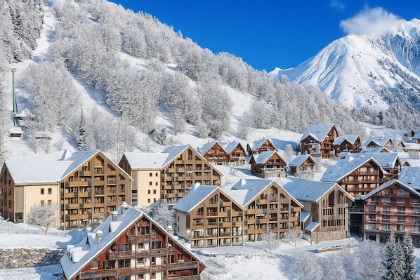 A snow-covered mountain resort with wooden lodges and a ski lift. - Alpine Home with Wellness Access (VAUJANY (ISERE))