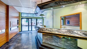 A modern lobby with a marble reception desk, wooden paneling, and a glass entrance. - Stay for 7 near Luchon-Superbagnères (Bagnères-de-Luchon)