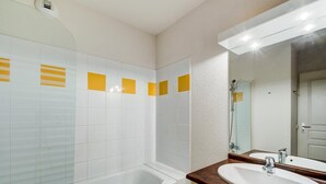 A bathroom with white tiles, a bathtub, a sink, and a mirror. - Stay for 7 near Luchon-Superbagnères (Bagnères-de-Luchon)