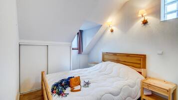Un dormitorio con cama de madera, una mesita de noche, una lámpara de pared y una ventana.