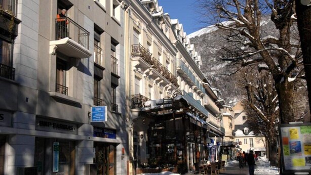 Un immeuble à plusieurs étages doté de balcons, une enseigne indiquant un restaurant et une rue recouverte de neige.