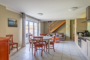 Un comedor con una mesa redonda y sillas, un sofá, una cocina con estufa y una escalera.