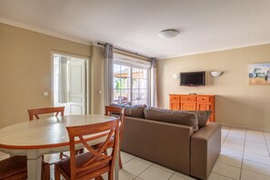 Un comedor con una mesa y sillas, un sofá, un televisor y una ventana con cortinas.