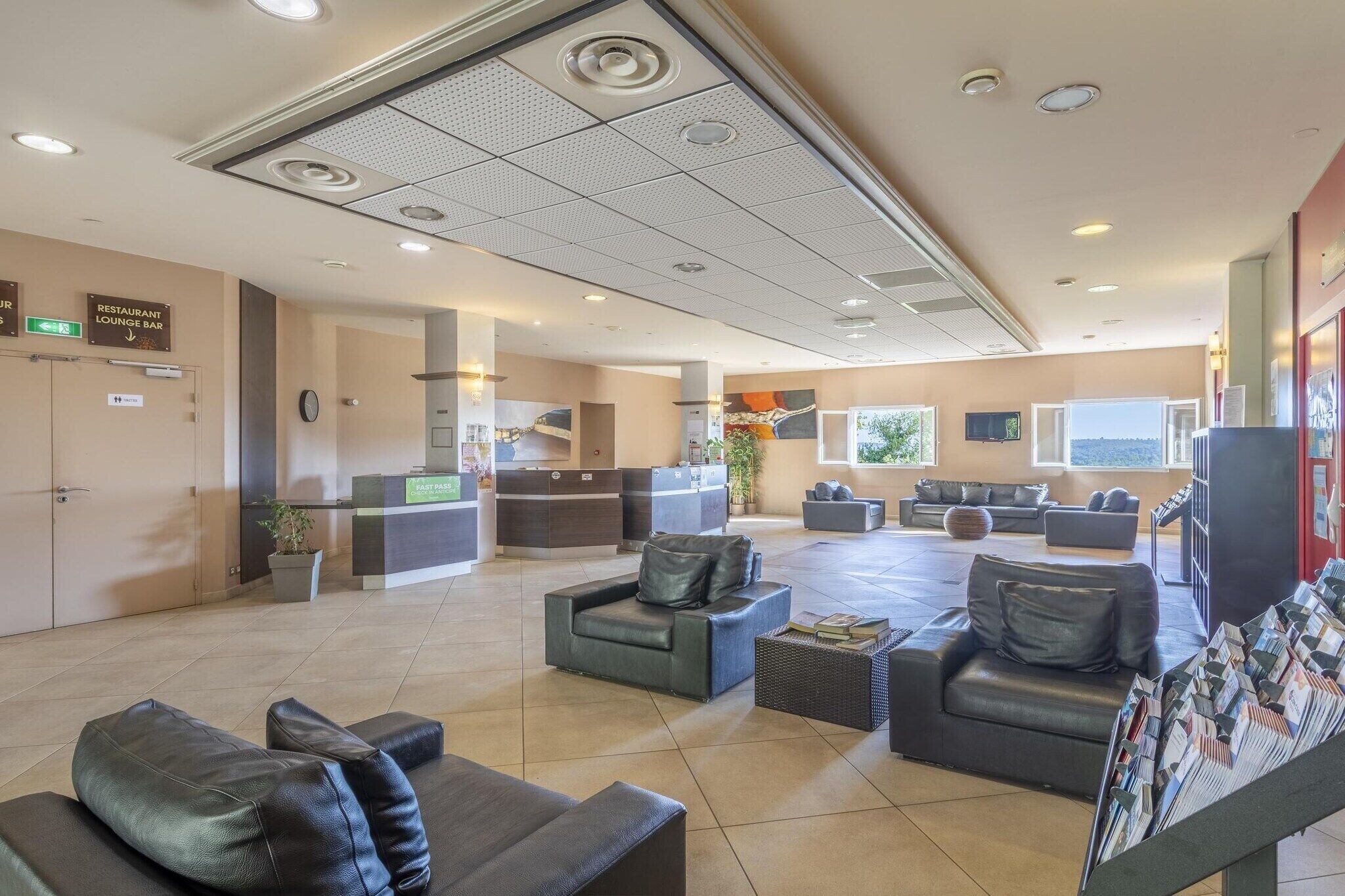 A hotel lobby with seating areas, a reception desk, a restaurant, and a lounge bar.
