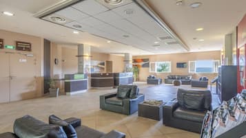 A hotel lobby with seating areas, a reception desk, a restaurant, and a lounge bar.