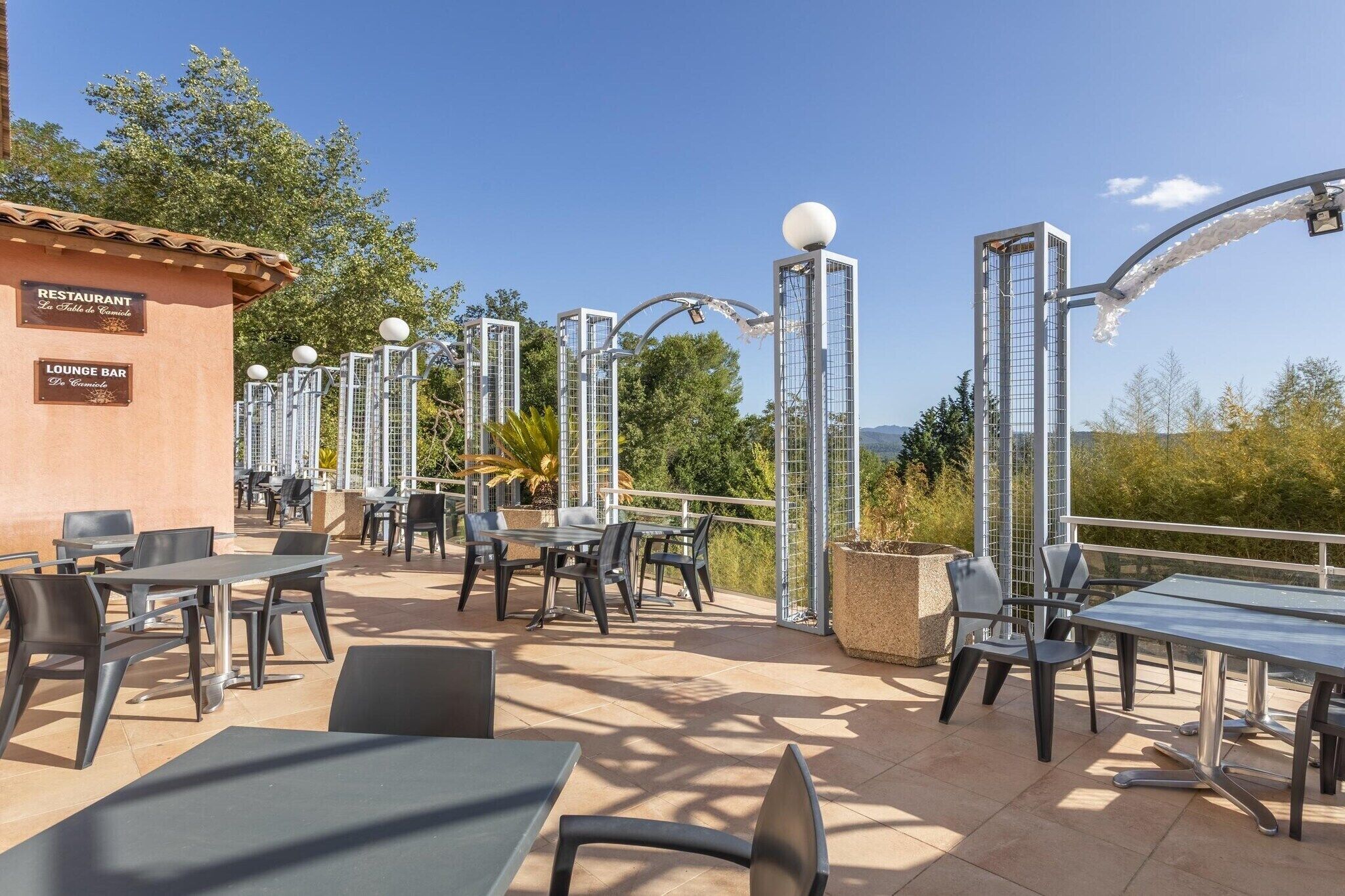 An outdoor patio area with tables and chairs, a restaurant sign, and a lounge bar sign.