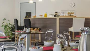 Een restaurantgedeelte in een hotel, met een balie, stoelen, tafels en een klok aan de muur.